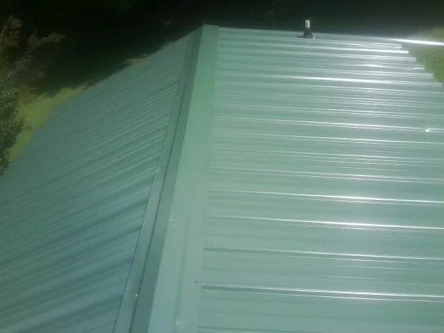 New green metal panels meeting at the ridge of a roof — Flat Roof Repair work by our crew in Pacific Palisades
