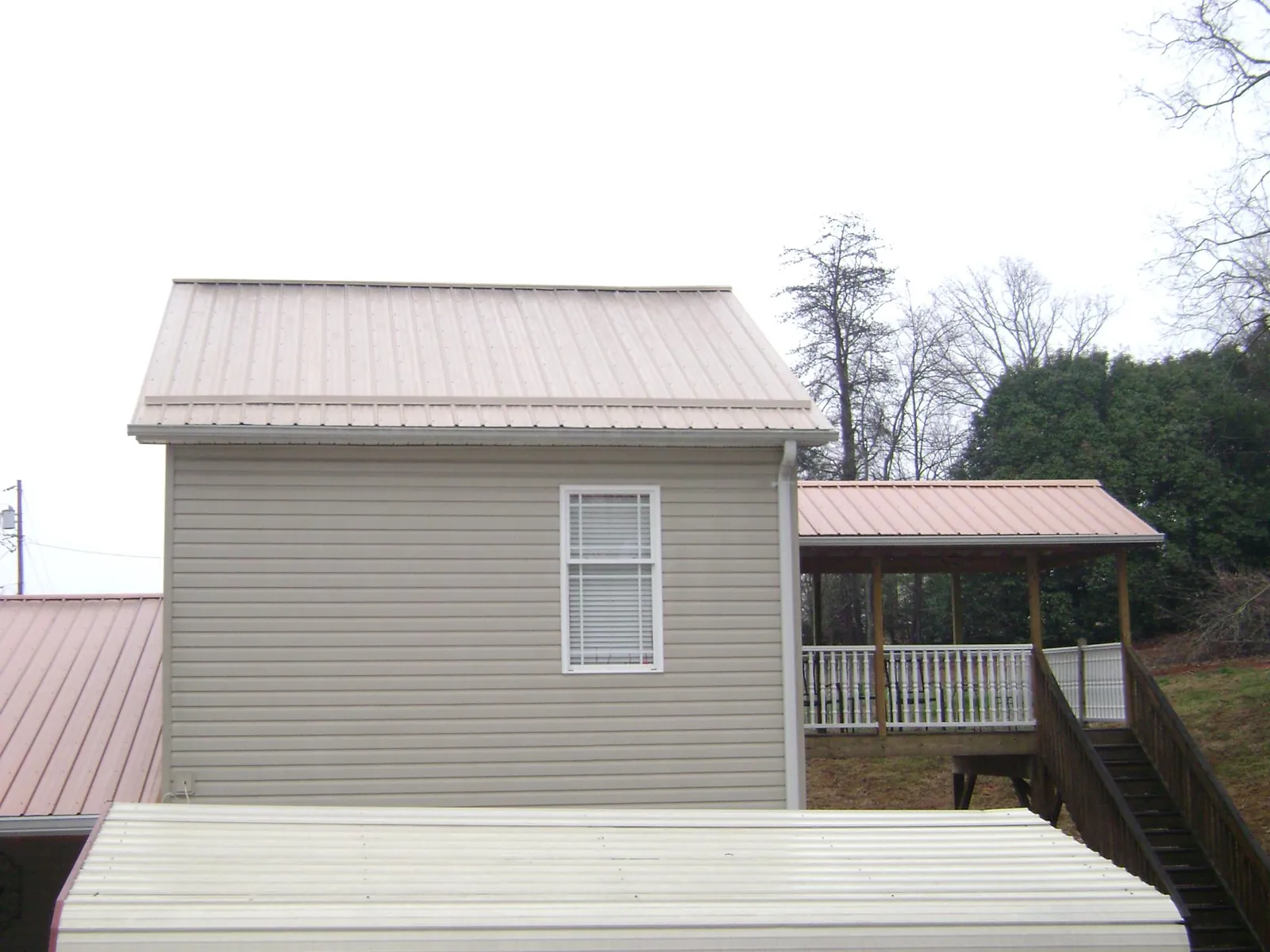 Tan metal roofs on a two story addition and attached porch, from a Roof Replacement job in Pacific Palisades