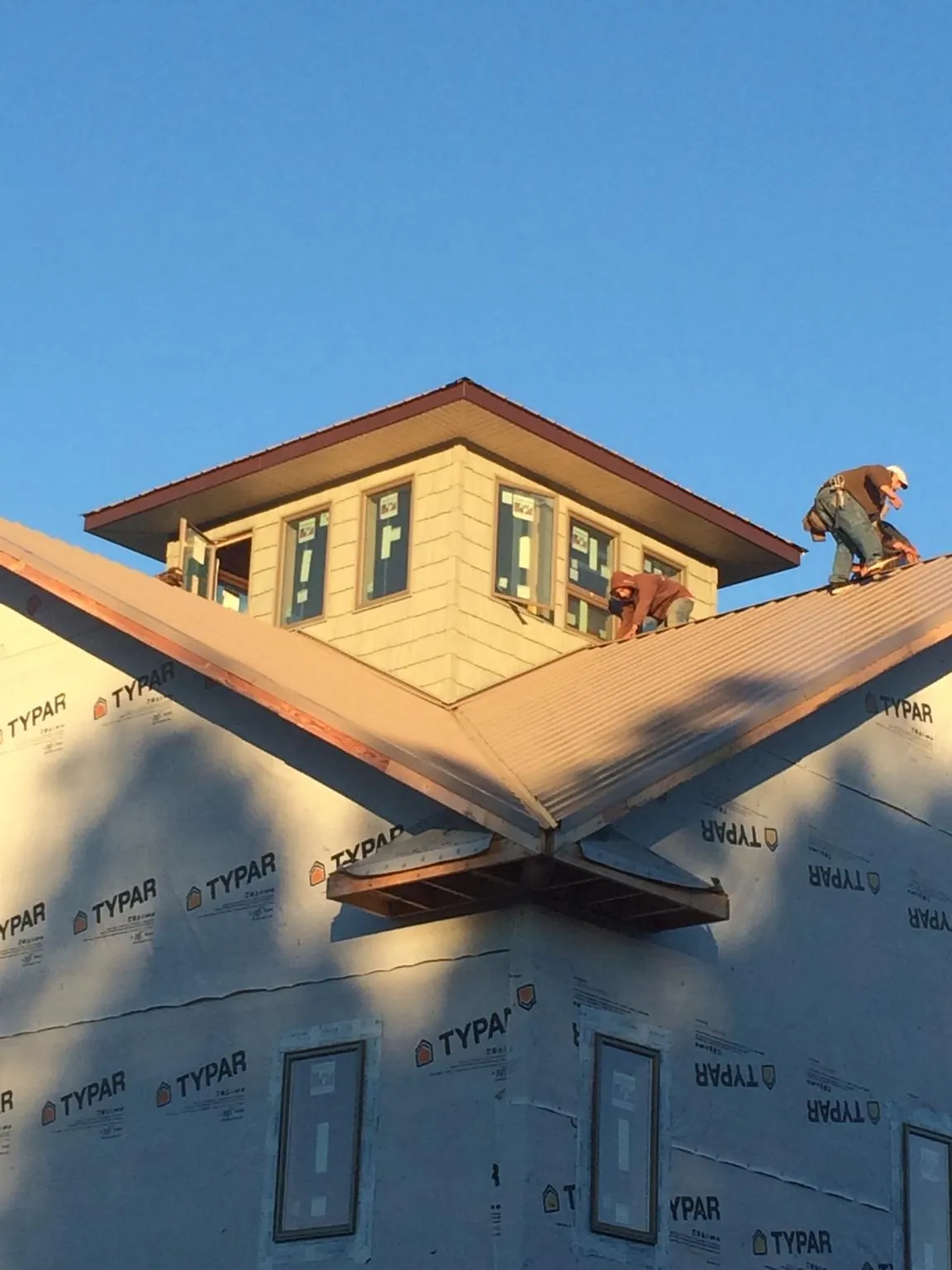 Roofers working around a rooftop cupola on a new metal roof at sunset — Roof Waterproofing in Pacific Palisades by Roofing Brothers